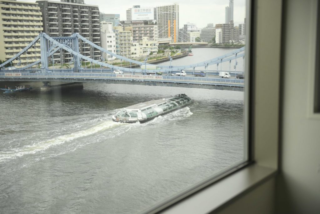 客室はバスルームから隅田川を望むレイアウト。窓の外には船が行き交う。