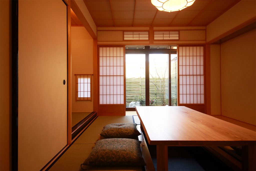 掘りごたつ式の座敷は端正な和の空間。玄関の花台には、あえて花を生けていない花瓶が置かれ、花を買って空間を装う楽しみも密かに提案されている。 s_IMG_2455_1