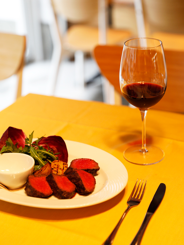 国産黒毛和牛A5ランク熟成肉ランプ（150g）3,900円～、赤ワイングラス600円～（各税込）。ワインリストはイタリアの自然派中心。ボトルは2,980円～とリーズナブルに楽しめる。