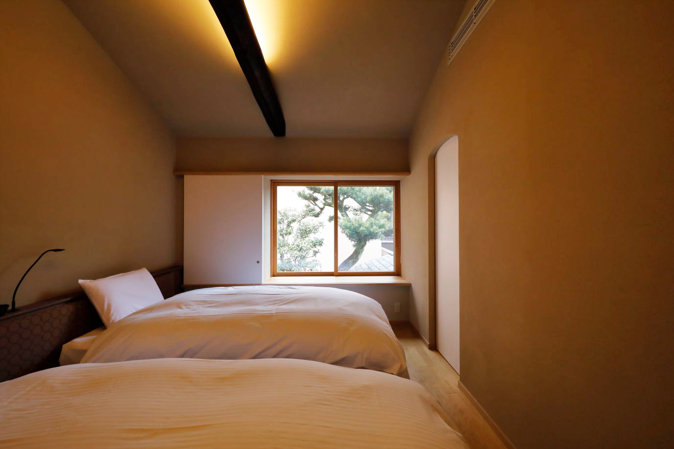 シングルベッドが2台並ぶ寝室。窓からは樹齢100年のイヌマキの古木が。