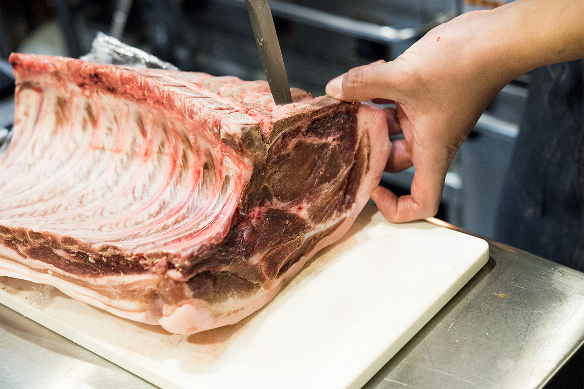 千葉県産の仔豚の骨付き肉は、ロースとバラ2つの部位を一度に味わえる。