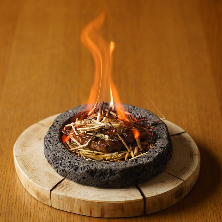 溶岩石と藁を使ったメイン料理「山梨牛黒胡椒焼き」はテーブルで炎をあげて仕上げる演出。 山梨 ふふ 河口湖