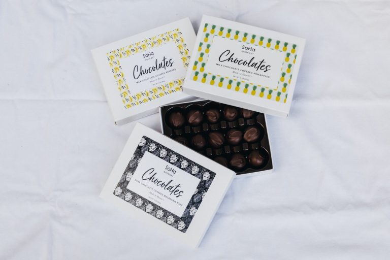 洗練されたパッケージのチョコレートは、どれも甘さを抑えた大人の味わい。右・ミルクチョコ×パイナップル(ジャム)、左・ミルクチョコ×バナナ(ドライ)、下・ダークチョコ×マカダミアナッツ。各11.8ドル。 _56A4142