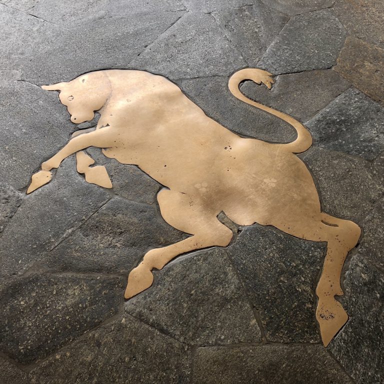 店先の床面に描かれた真鍮の雄牛。ここでも股間の上をかかとで回ることで幸運が訪れると言われている。