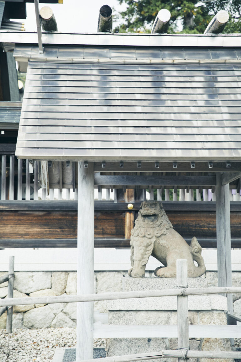 屋根に守られた狛犬は鎌倉時代に作られた石造りで、魔除けの力があると伝わる。どことなく愛らしい表情で、模した土鈴もある。