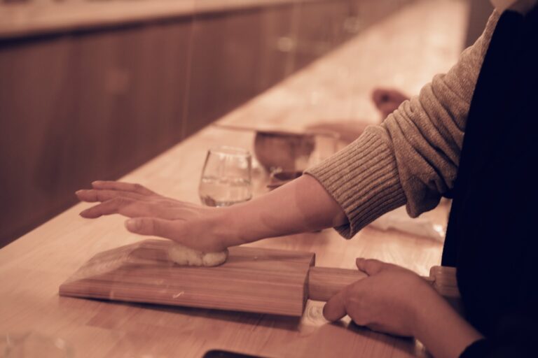 「ひねり餅体験」では蒸米を木製スコップ「ぶんじ」の上で押し潰し、ねって餅のような形に整えていく。