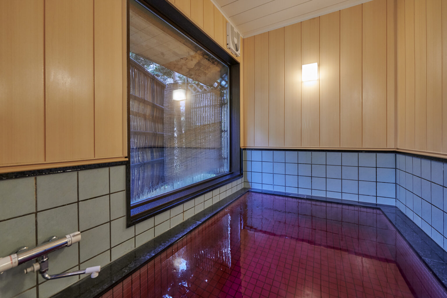 パープルの色が鮮やかなワイン風呂。浴室の窓からは日本庭園が見られる。