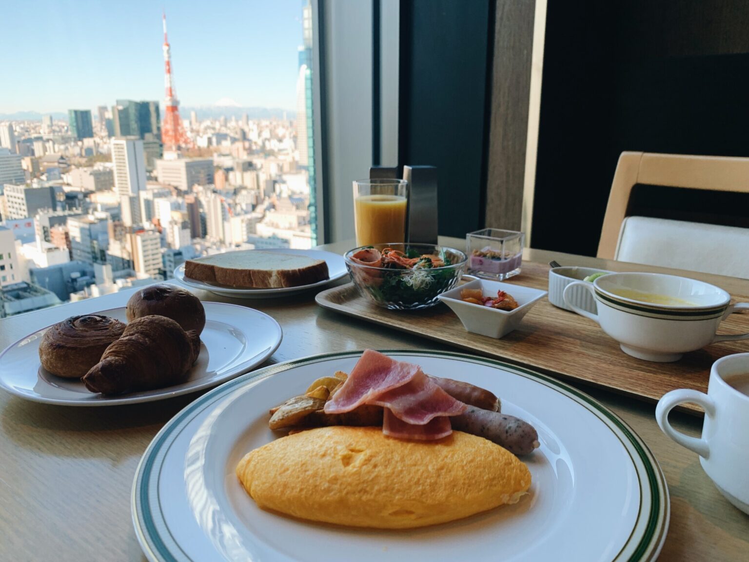 〈ハーモニー〉のアメリカンブレックファースト（7:00~10:00）は、４種類の卵料理から一つ選ぶプリフィクススタイル。前菜プレートやサラダが付くほか、パンやドリンクはブッフェカウンターからお好みで。窓の外には東京タワー、天気が良ければ富士山も！