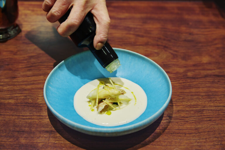 本日のディナーコース 22,000 円より、ホワイトアスパラの冷たいスープ・文旦とはまぐりの香り。アスパラの甘みに春の苦みが表情を添える。青木浩二氏の青の器で。