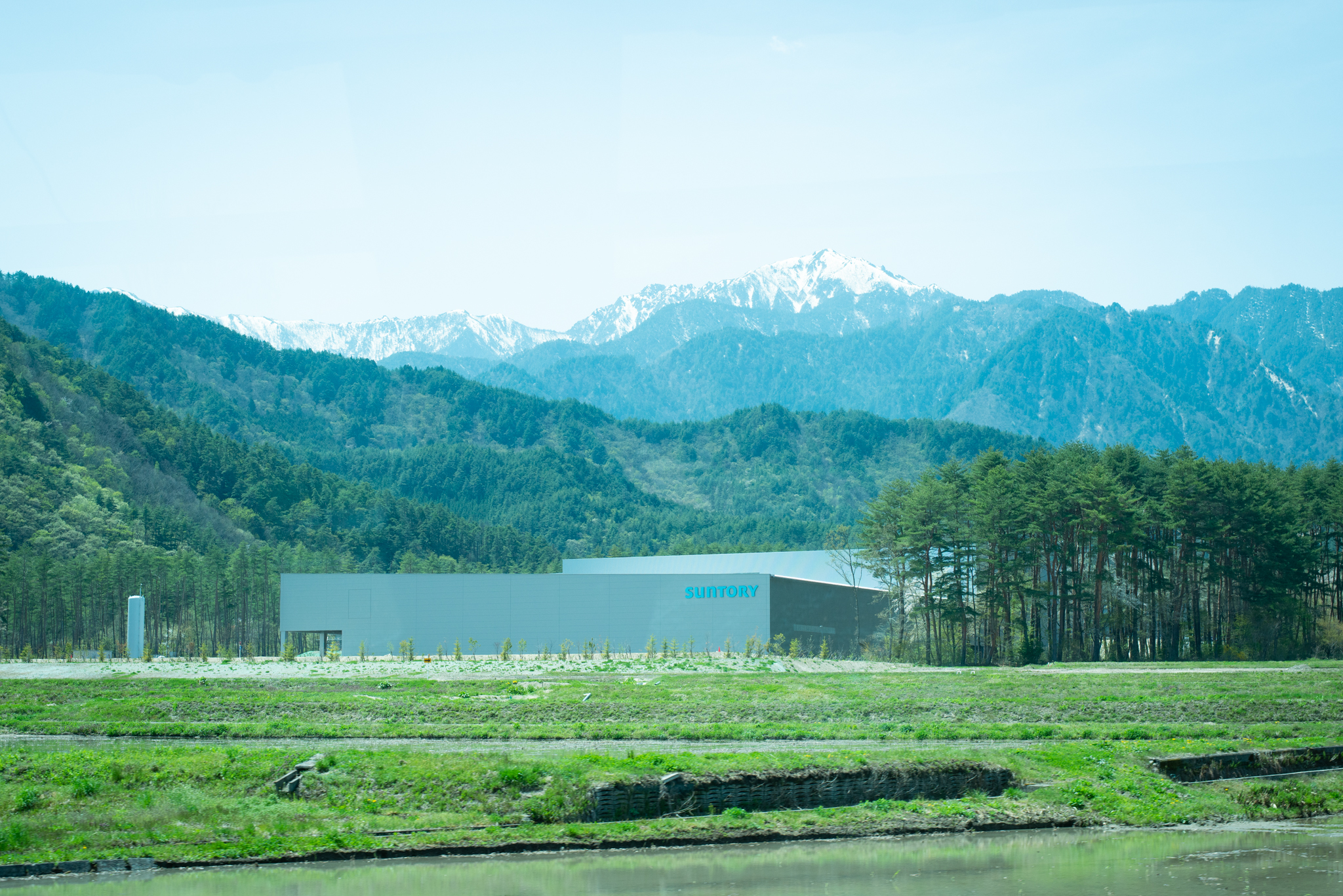 〈サントリー天然水 北アルプス信濃の森工場〉の外観。工場の背景には、美しく雪化粧した北アルプスがそびえています。