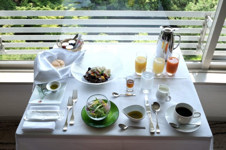 ジュース、彩り野菜サラダ、5種のフルーツの豆腐ピューレボウル、ライスブレッド、コーヒーがセットになった朝食。
