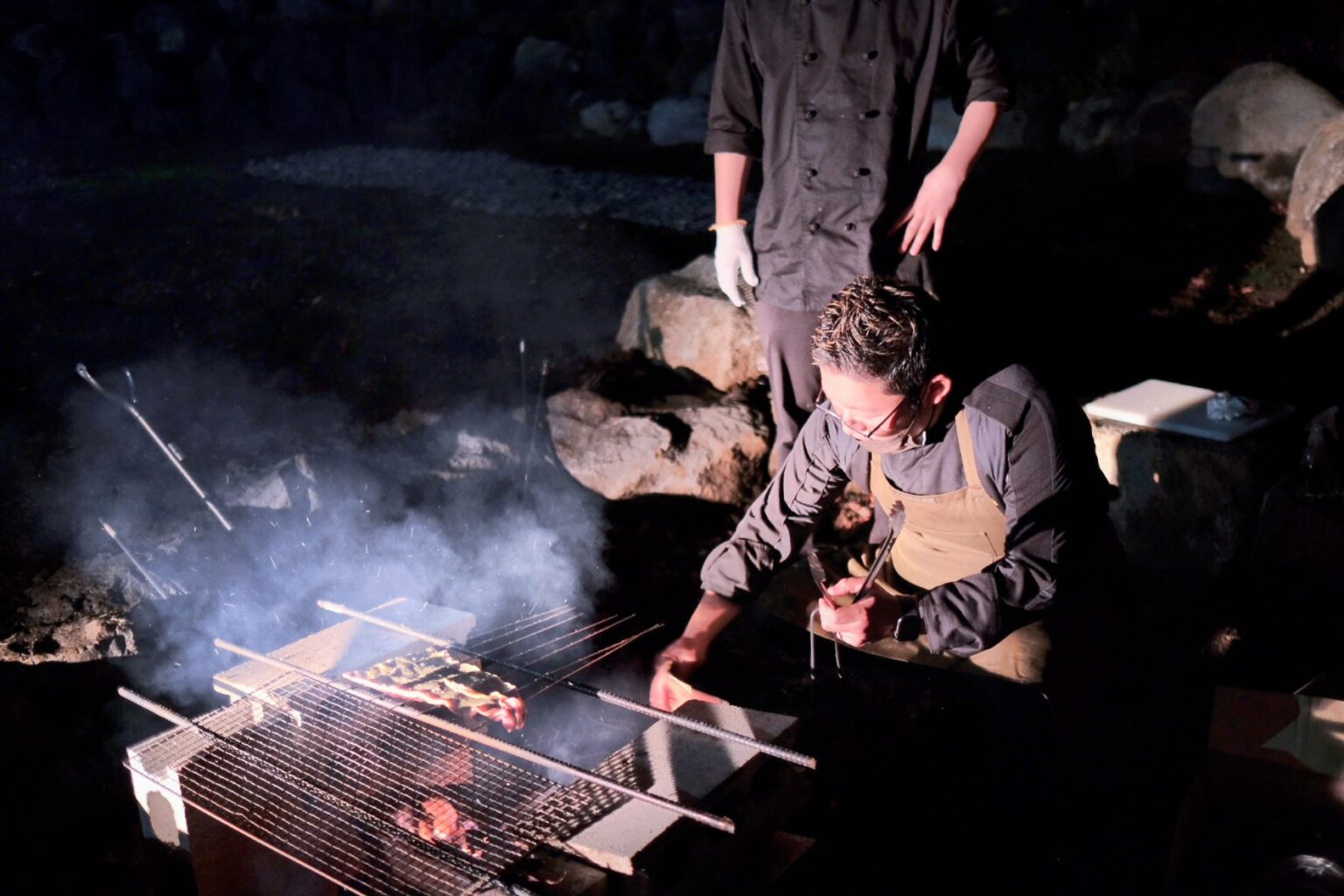 ナラやヒノキの薪火でナマズや鹿肉を火入れするシェフたち。