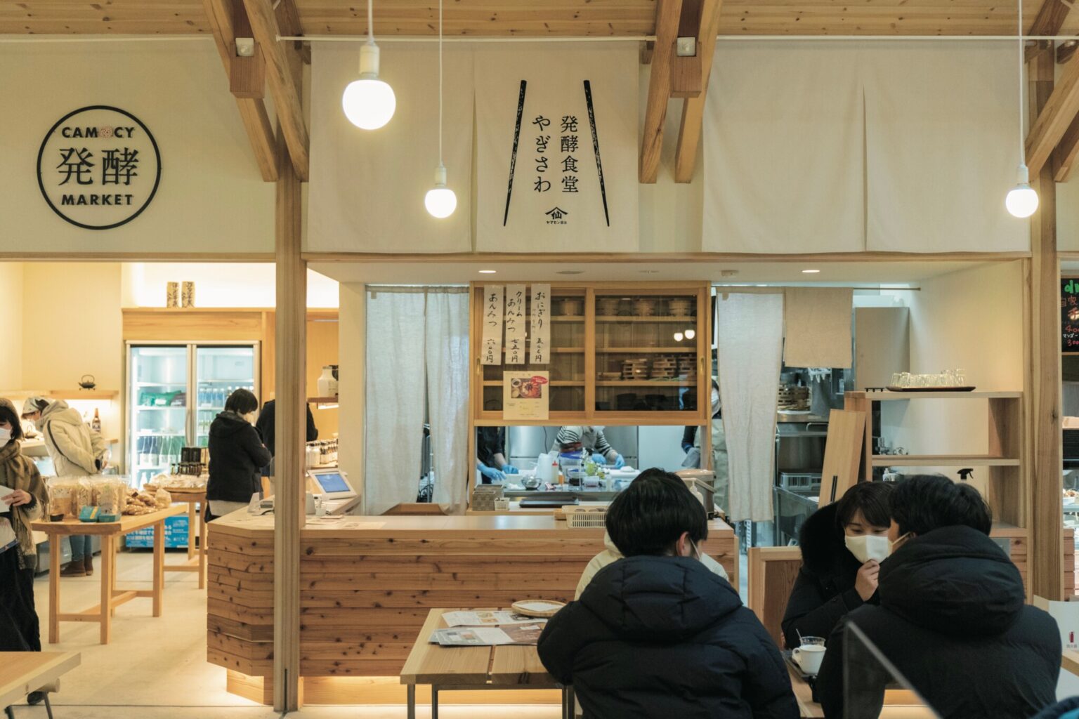 岩手県陸前高田市にある発酵テーマパーク〈CAMOCY〉。中央のフードホールを、7つの店舗がぐるりと囲む。みんなで集う人、ひとりでくつろぐ人、思い思いの楽しみ方で過ごす憩いの場。
