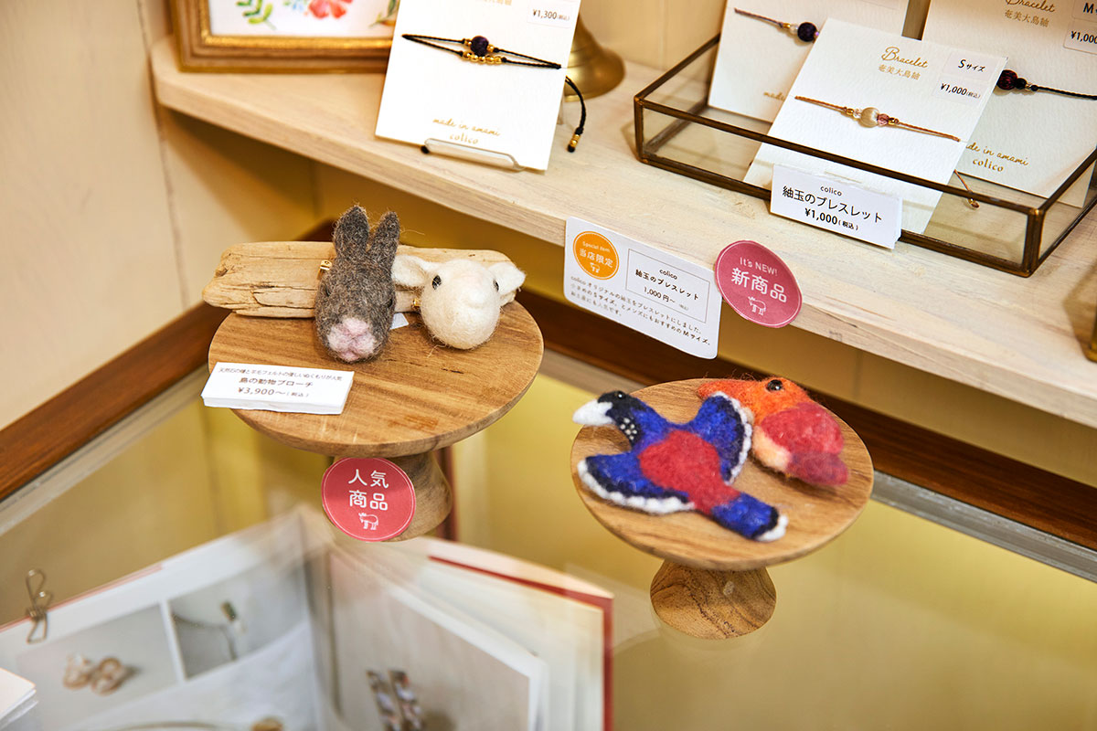 大島紬の紬玉のブレスレットも人気。奄美に生息する生き物をモチーフにしたブローチはフェルト作家KIKURAさんの作品。