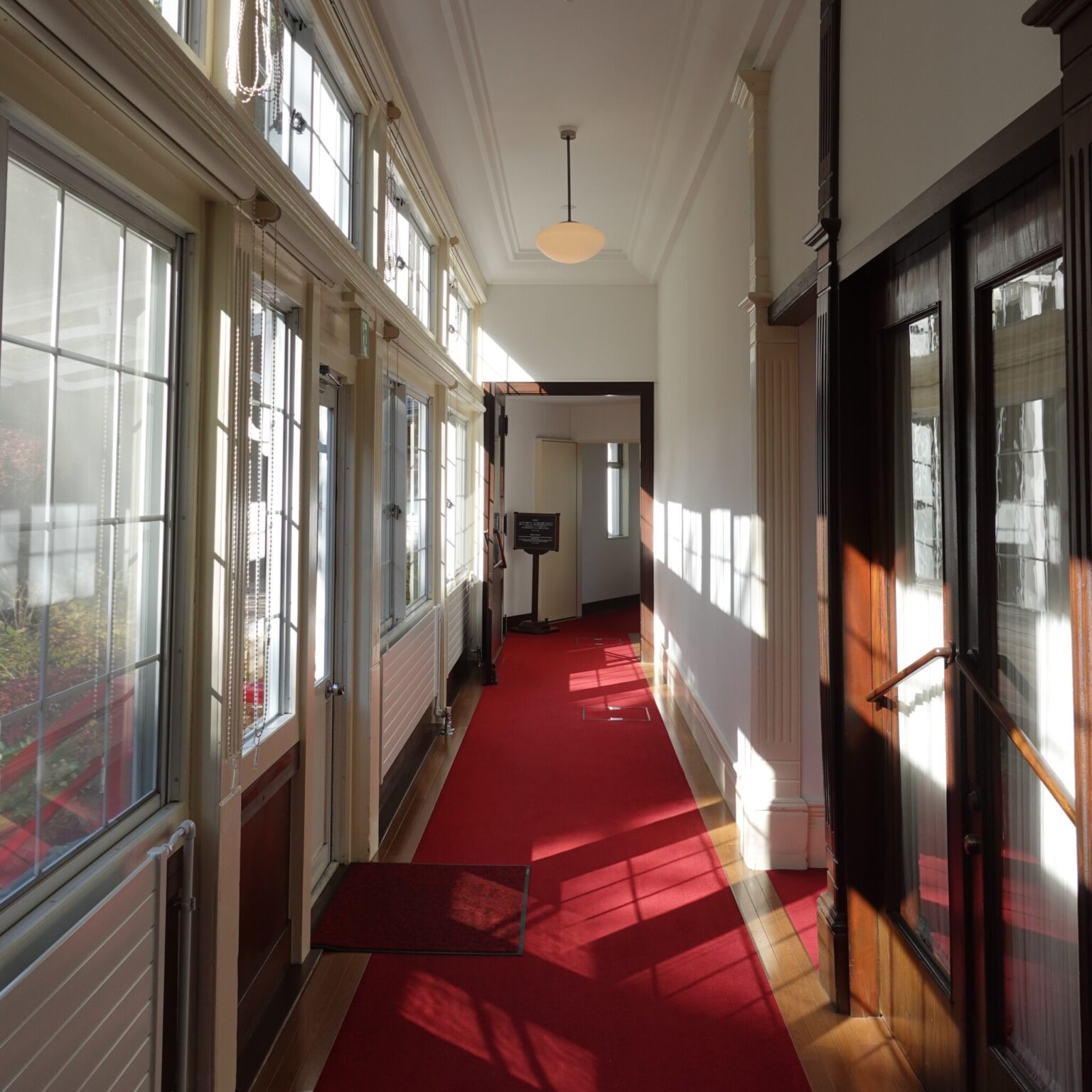 廊下は、陽光に映える赤じゅうたんと白亜の壁。