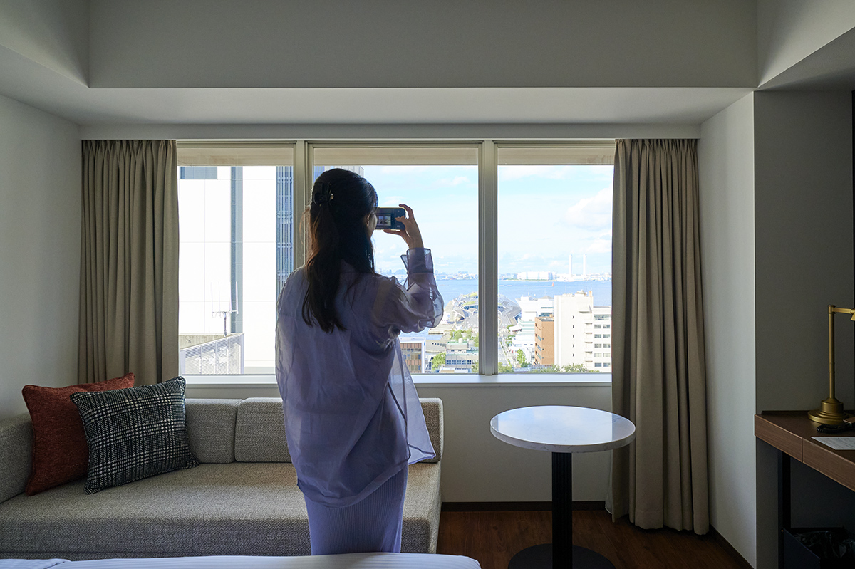 イベントは客室ツアーからスタート。窓から見える横浜の景色を撮影するハナコラボ パートナー。