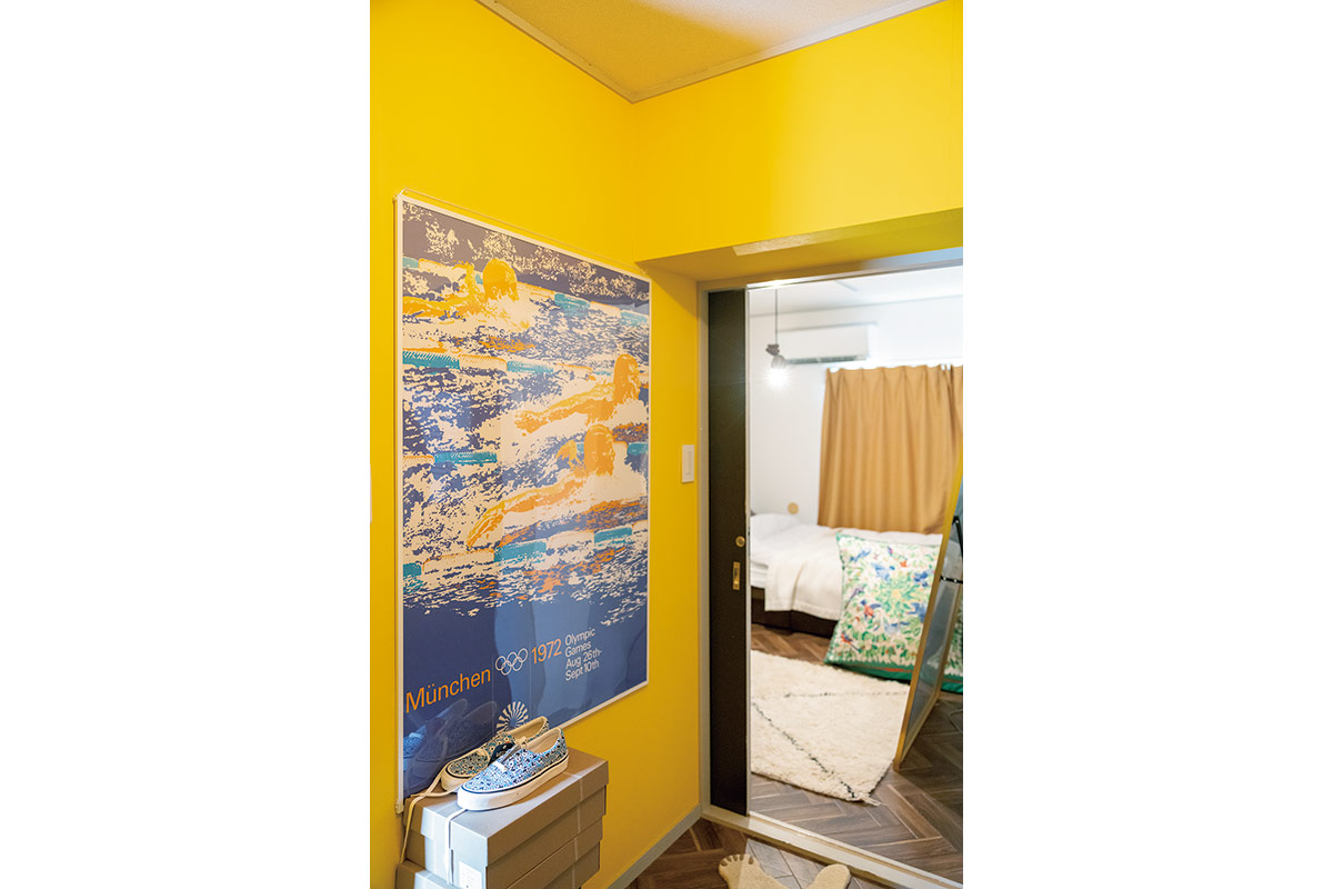 2.黄色に塗った壁と、オリンピックポスター。スニーカーのコレクションやスカーフで自作したクッションカバーに、竹林さんの歴史が表れる。