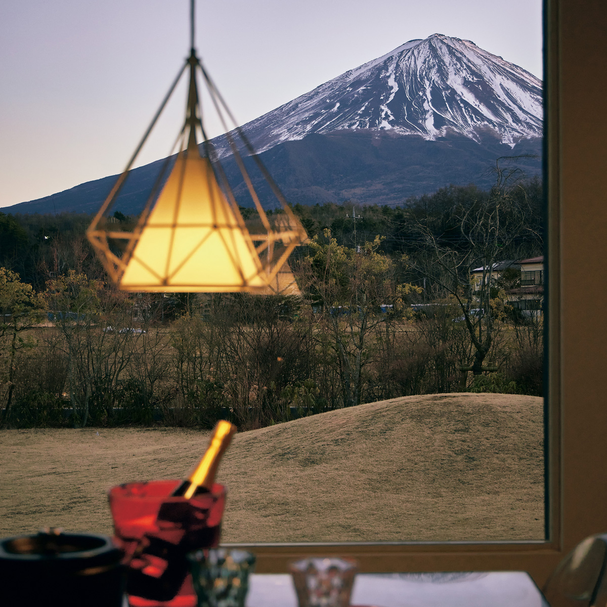 ダイニングキッチンの窓いっぱいに広がる日没間近の富士山。食事ができるまでのアペリティフタイムは、勝沼産のスパークリングワインを相棒にゆるりと過ごしたい。