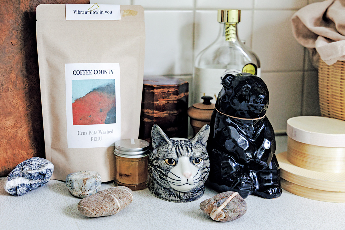 日々使う茶葉やコーヒーはしまい込まずキッチンカウンターに。さりげなく置かれた石のオブジェと猫のエッグスタンド、日本酒「ポンエペレ」の熊ボトルも愛らしい。