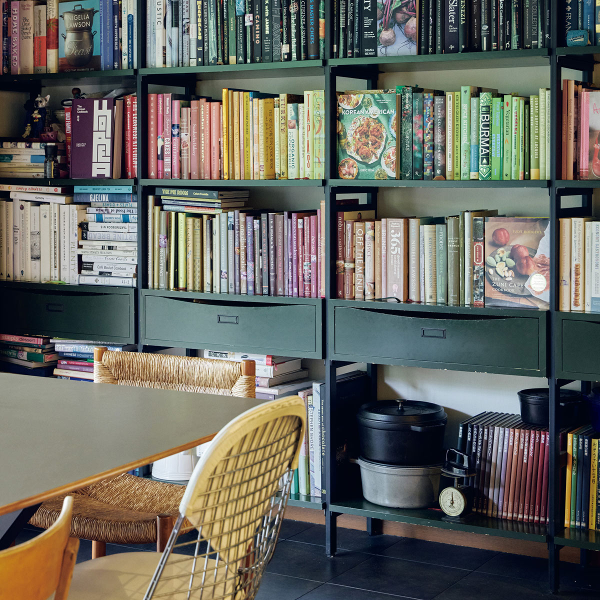 ダイニングには色別に料理本が並ぶ壁一面の本棚が。「前の家のサイズでオーダーした本棚がこの家にもぴったり。テーブルの天板も自分たちで張り替えたものです」