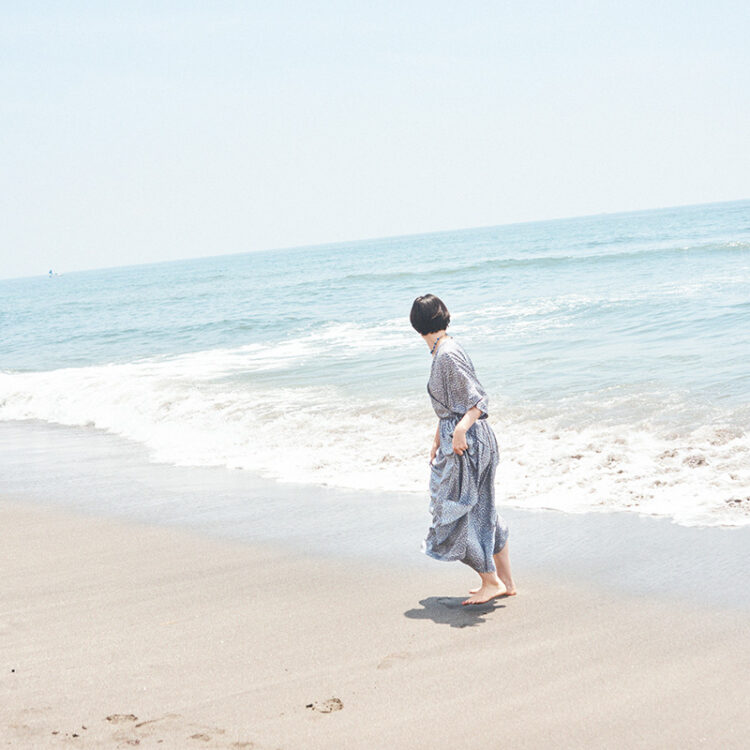 風通しのいいワンピースはビーチの必需品。海辺に映える華やかな花柄と存在感のあるネックレスで気持ちを上げて。カシュクールドレス132,000円（トゥジュー｜トゥジュー 代官山ストア 03-5939-8090）／エインシェントビーズネックレス42,900円（モチヅキ｜モット ハウス トーキョー 03-6325-2593）