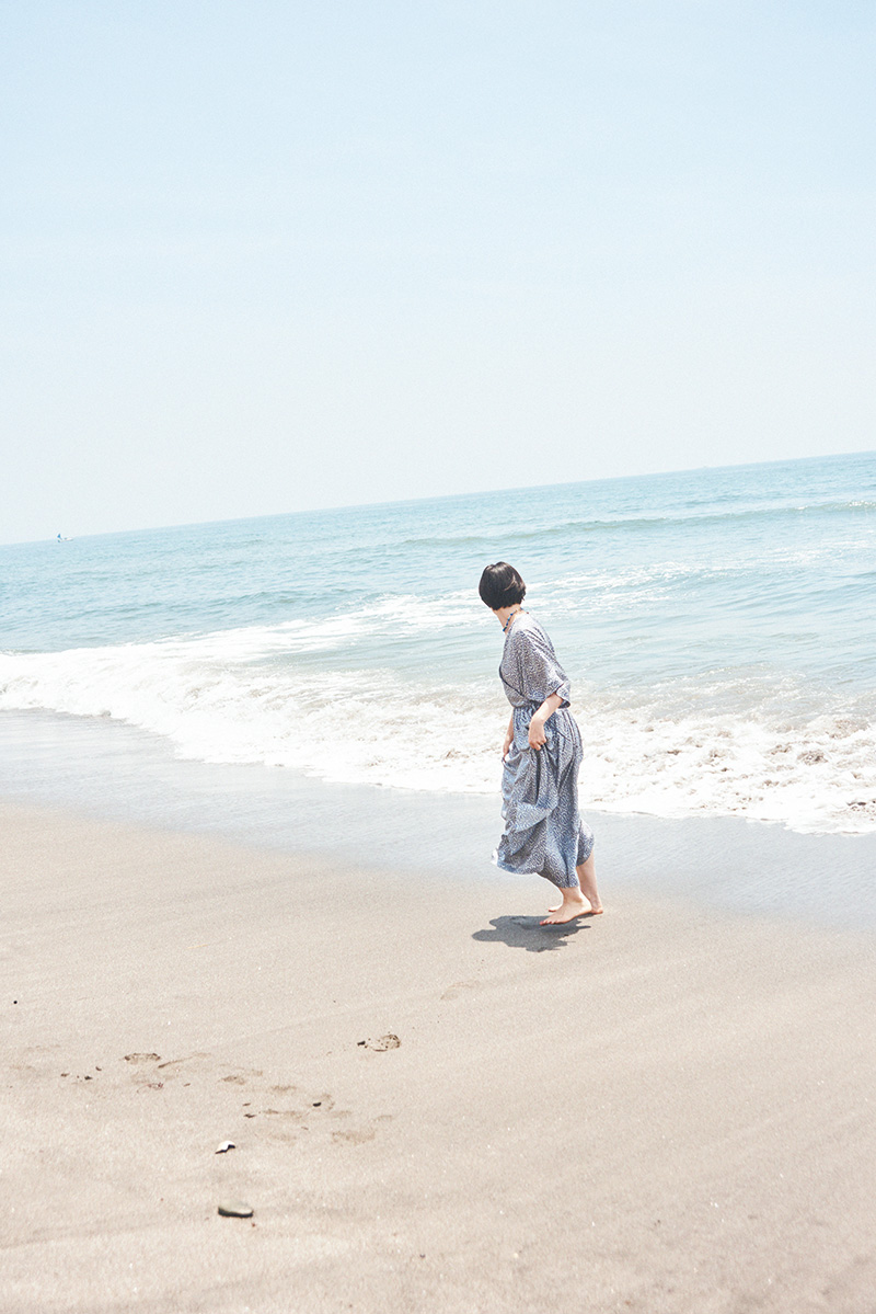 風通しのいいワンピースはビーチの必需品。海辺に映える華やかな花柄と存在感のあるネックレスで気持ちを上げて。カシュクールドレス132,000円（トゥジュー｜トゥジュー 代官山ストア 03-5939-8090）／エインシェントビーズネックレス42,900円（モチヅキ｜モット ハウス トーキョー 03-6325-2593）