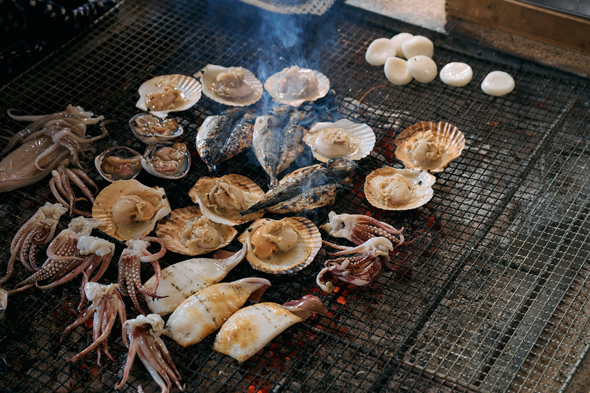 海女さんがふるまう炭焼きの海鮮ランチ「海女小屋相差かまど」でいかやサザエが焼かれる様子。