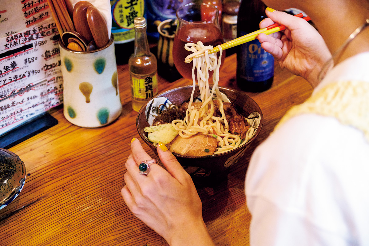 ブルーと透明なガラスのリングとシルバーのネックレスで涼しげに。お腹がぺこぺこだったので、三枚肉と特大ソーキがのった「全のせすば」（1,000円）をペロリ。〈亀浜製麺所〉のゆで麺と豚とカツオのWスープがほっこりおいしい。ガラスのリング16,500円（キーン｜モットハウス・トーキョー 03-6325-2593）