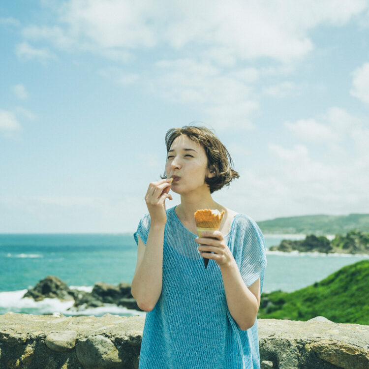 海岸でソフトクリームを食べる斉藤アリス