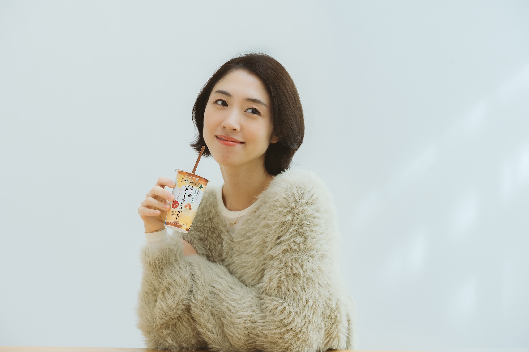 よつ葉乳業の「クリーム仕立てよつ葉バターキャラメルオレ」を飲む女性
