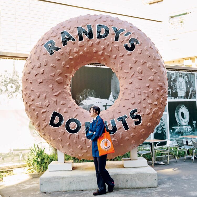 デニムワンピース55,000円（アー・ペー・セー｜アー・ペー・セー カスタマーサービス 0120-500-990）／中に着たストライプ柄シャツ27,500円（ホワイトサンド｜ティースクエア プレスルーム 03-5770-7068）／スウェットパンツ11,990円（ヒープ https://heap-underwear.com/）／ファーシューズ29,700円（クオディ｜メイデン・カンパニー 03-5410-9777）／トートバッグ3,740円（ランディーズドーナツ https://randysdonuts.jp/）