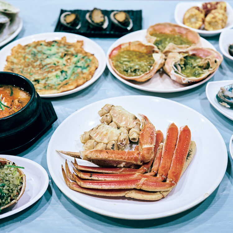 鮑の刺身、セウジャン、チヂミ、チゲなど1人 5,000ウォンの席料でたっぷりのおかずが並ぶ。 鮑の刺身、セウジャン、チヂミ、チゲなど1人 5,000ウォンの席料でたっぷりのおかずが並ぶ。