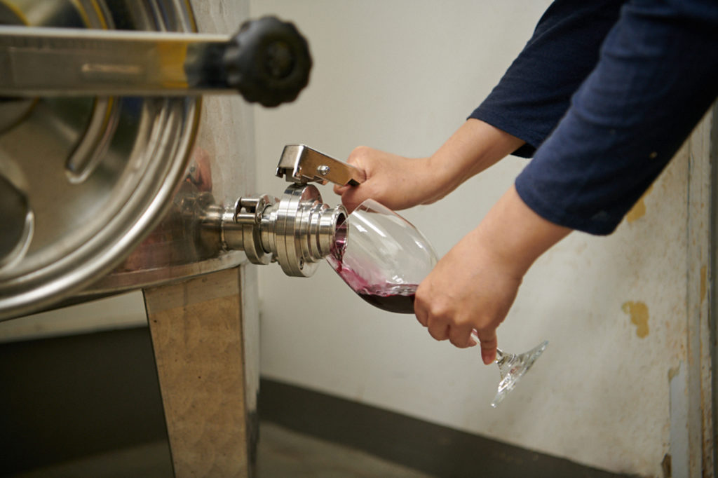 タンクに入っているワインを少量注ぎ、熟成度合いをチェック。理想の味になったら、無濾過のまま手作業で瓶詰めして出荷します。